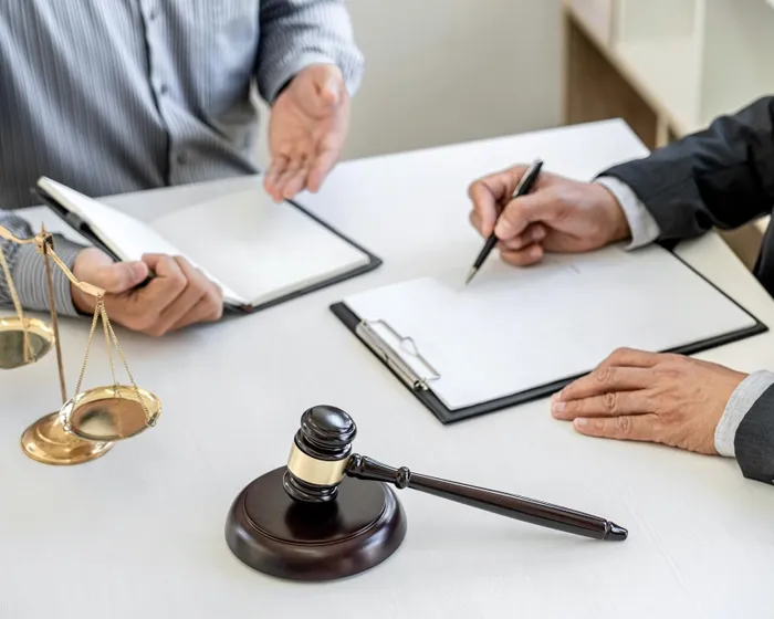 Two professionals reviewing legal documents beside scales of justice and a gavel